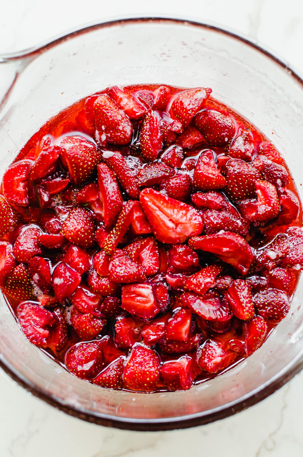 A bowl of sliced strawberries in juice.