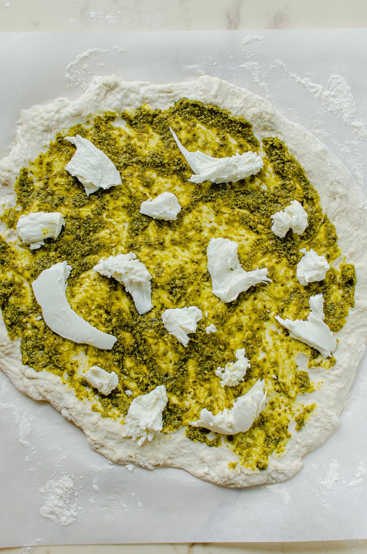 Pizza dough topped with pesto and fresh mozzarella.