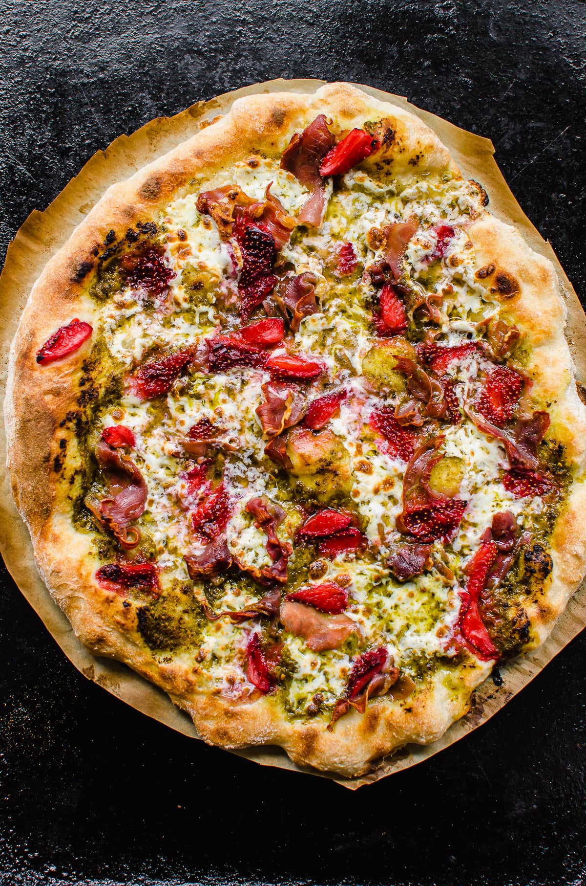 A baked prosciutto pizza with strawberries and pesto.