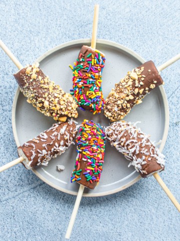 Chocolate-dipped frozen bananas on a blue plate.