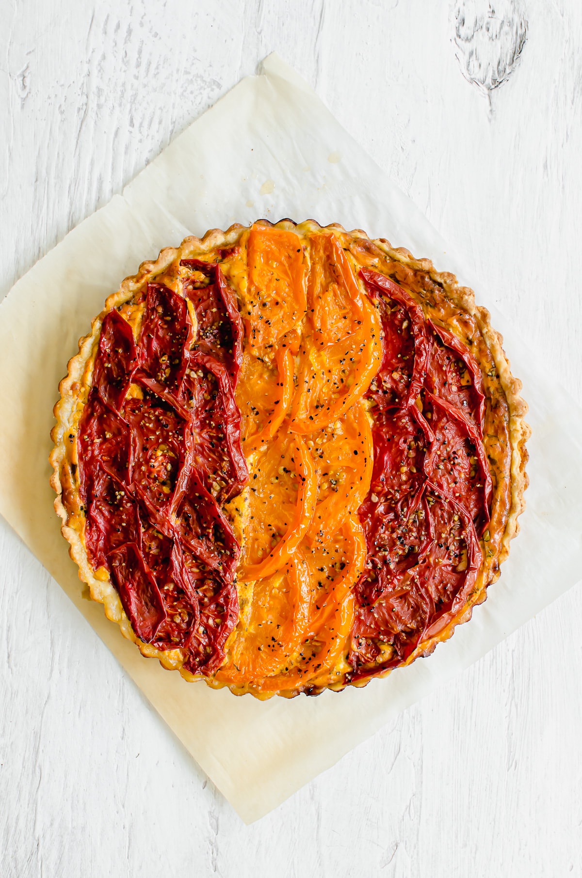 A baked tomato tart on a sheet of parchment paper. 