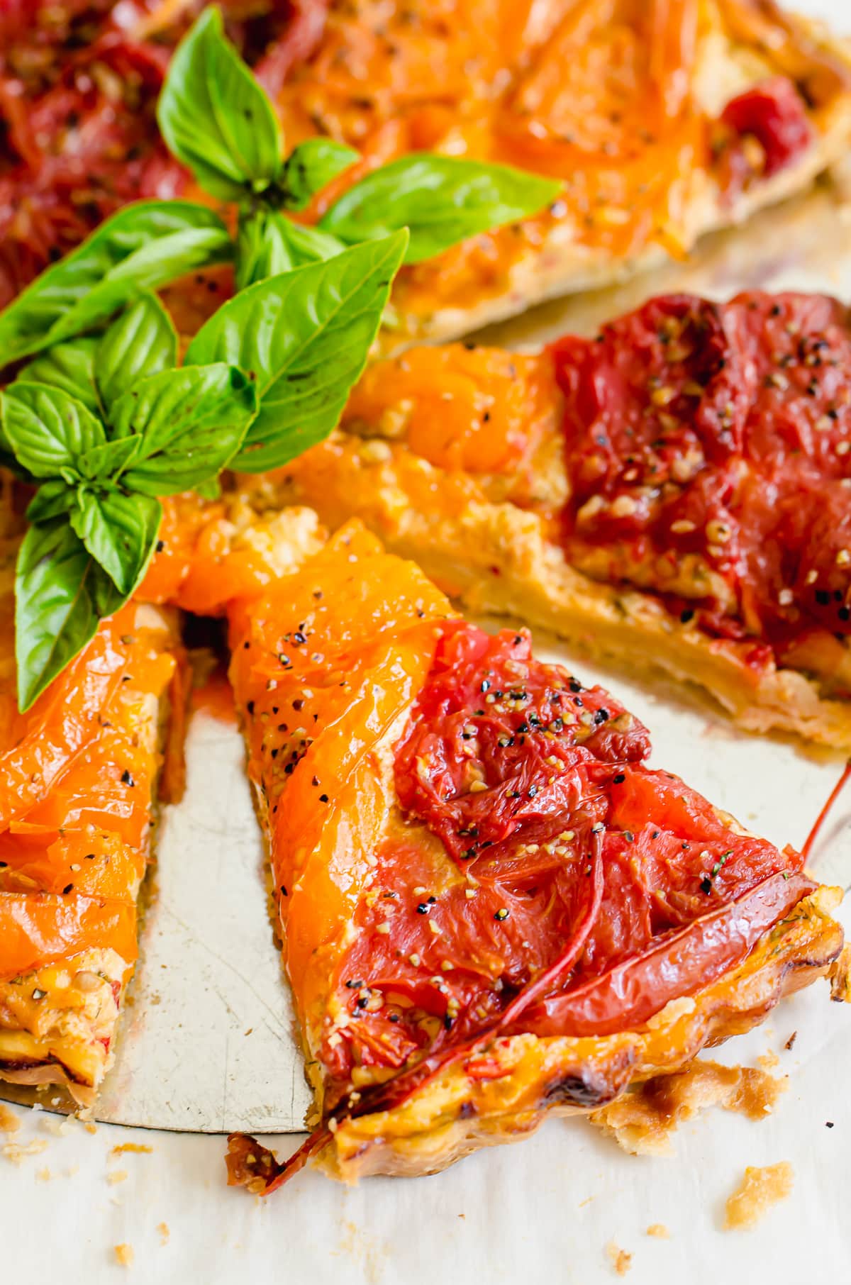 A slice of tomato tart coming out from the whole tart.