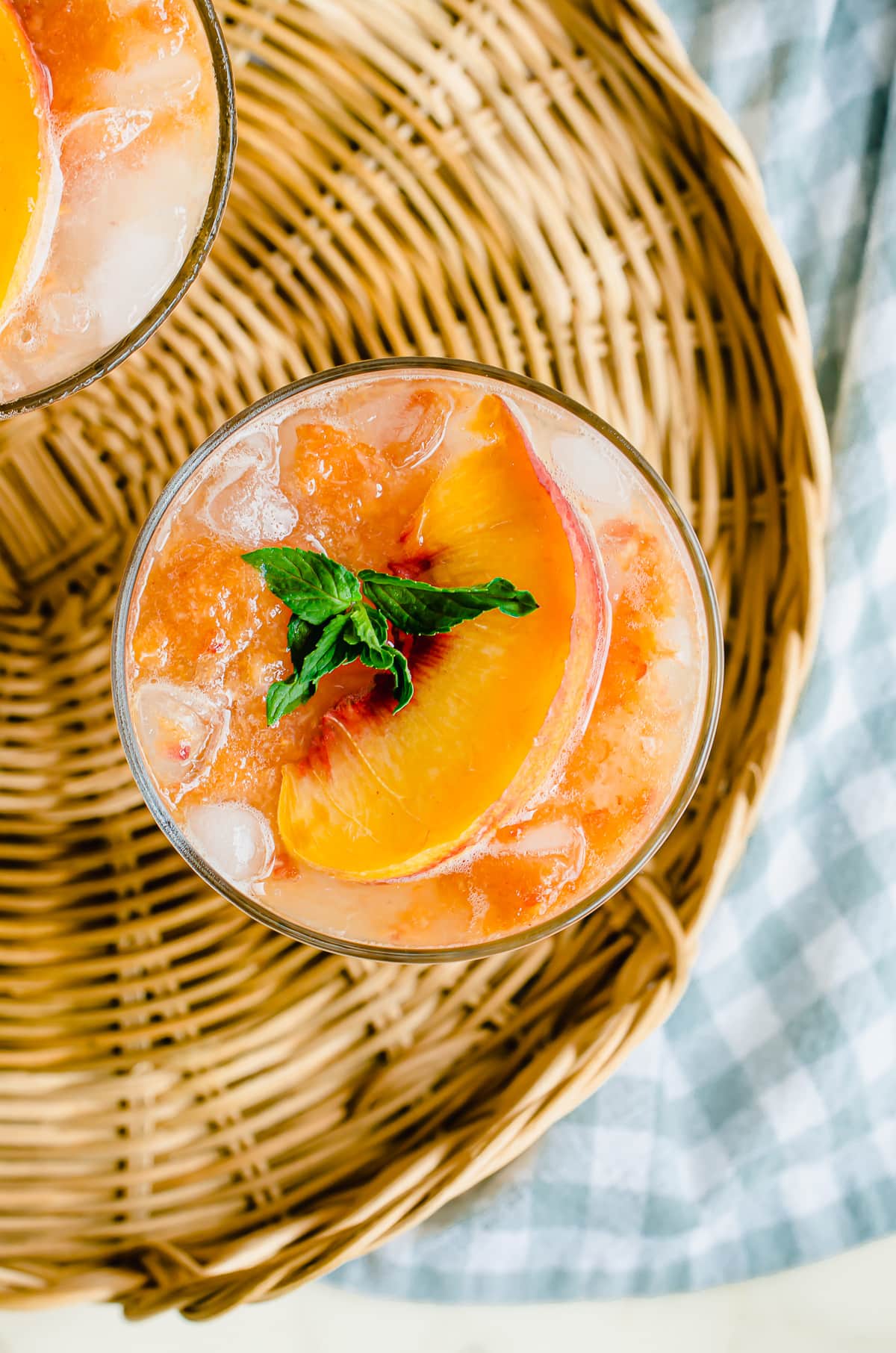 An overhead, close-up shot of a glass of lemonade garnished with a peach and mint sprig.