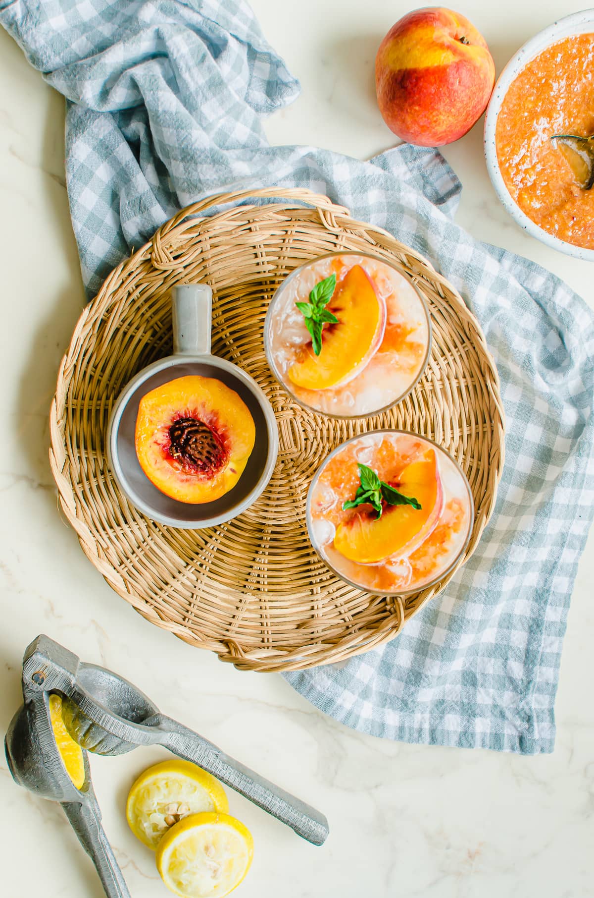 Overhead shot of styled glasses of lemonade with peaches and lemons on the side.