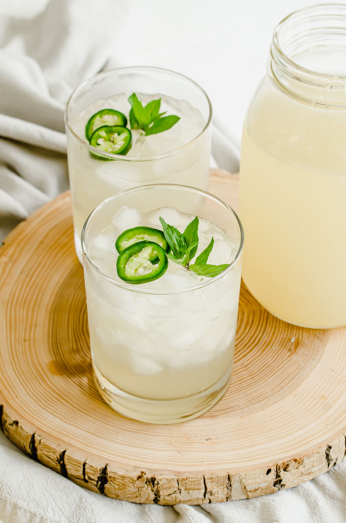 Glasses of lemonade with a large Mason jar of lemonade on the side.