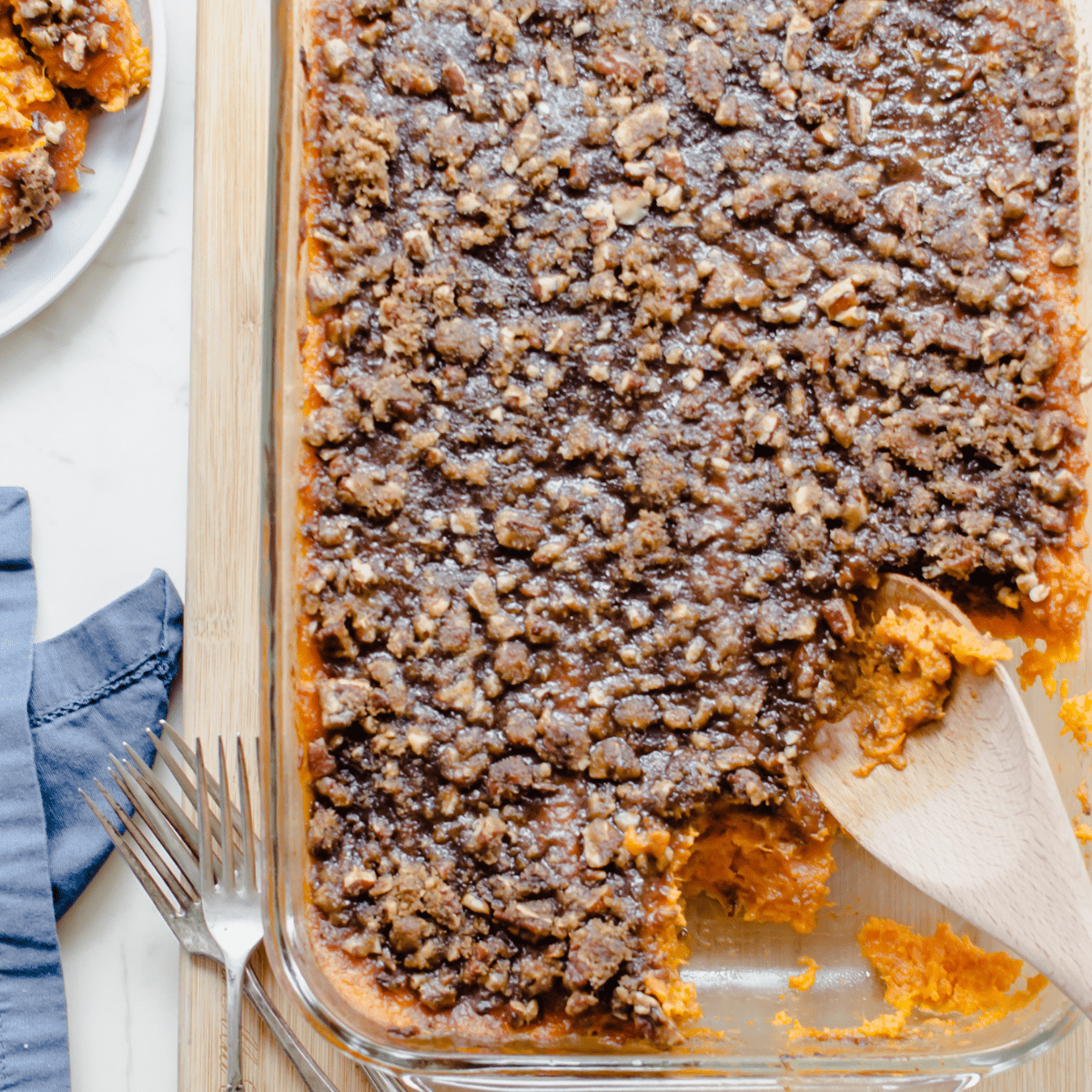 A large dish of sweet potato casserole with a spoon taking a serving out of the side.