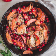Pan-fried pork chops in a cast-iron skillet with a cranberry apple pan sauce.