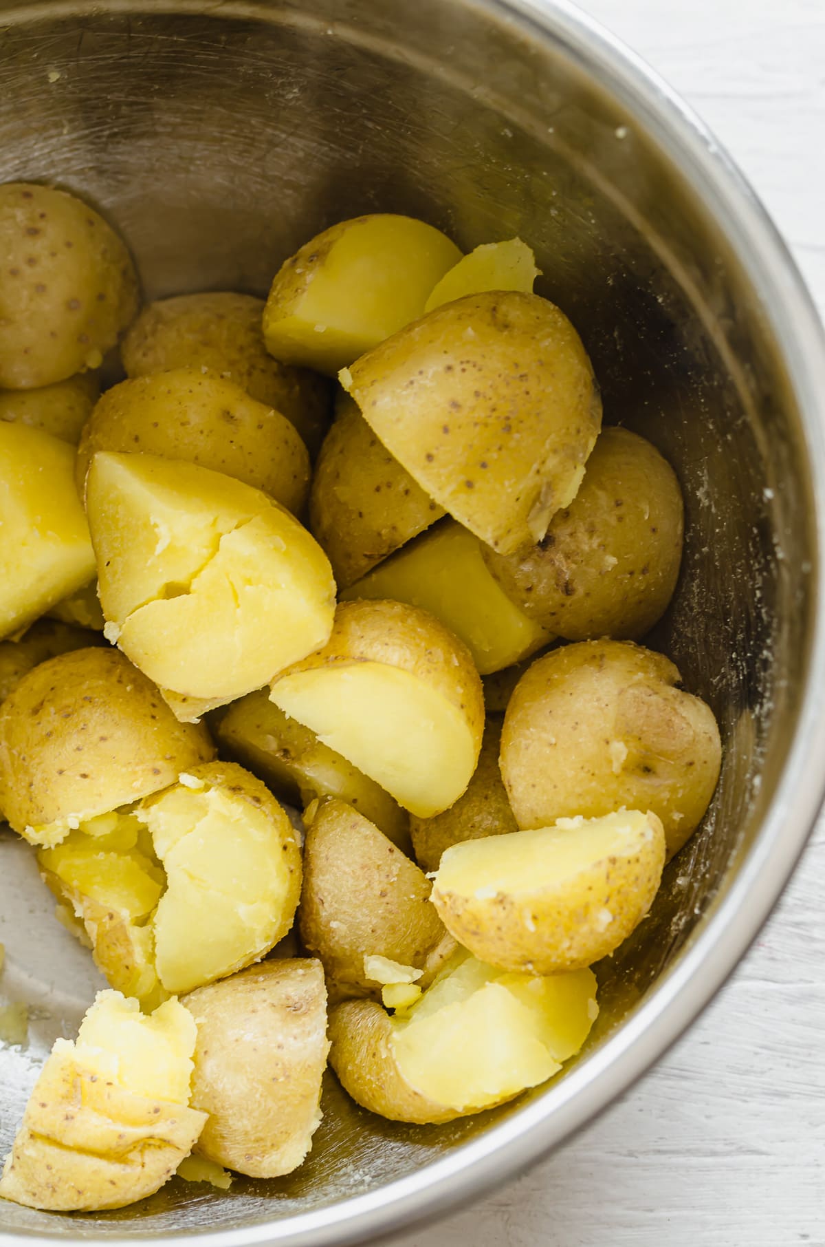 Sliced steamed potato pieces in a large silver bowl.