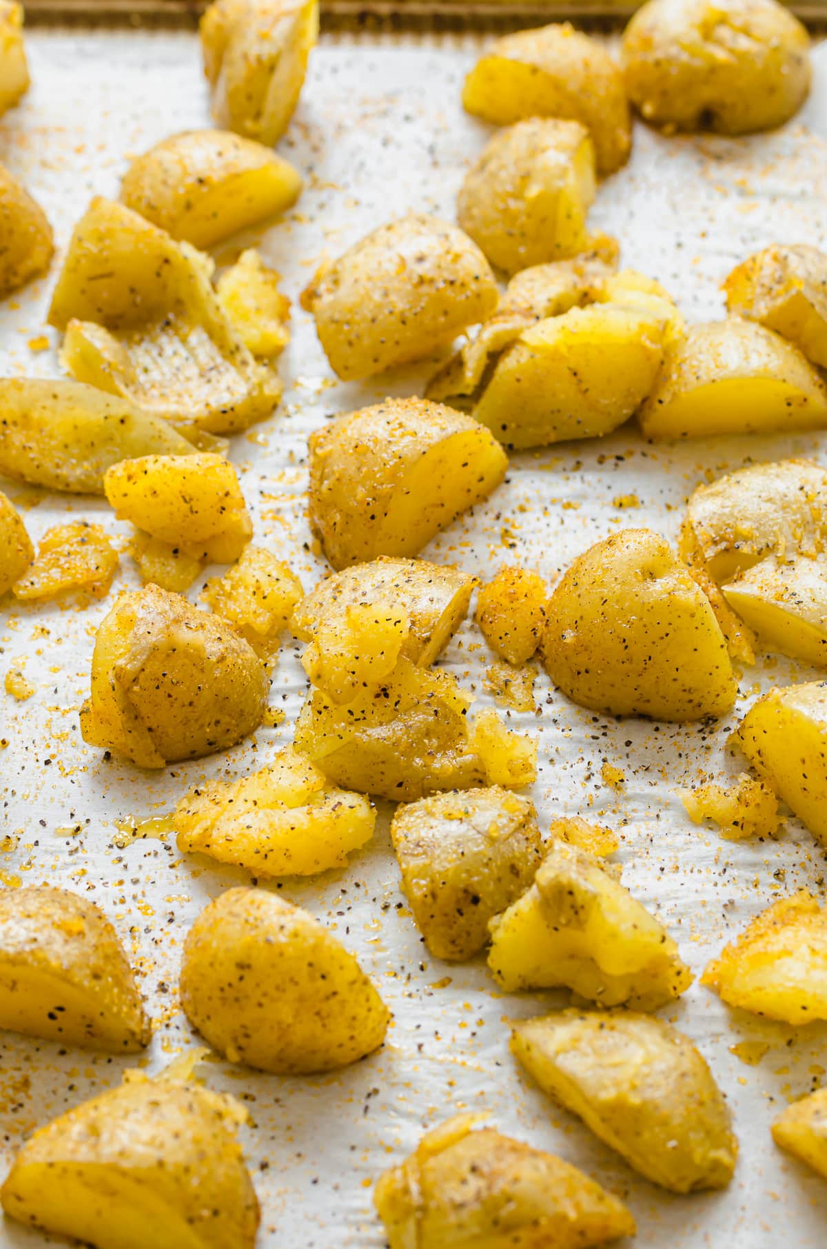 Seasoned, steamed Yukon gold potato pieces on a baking sheet.