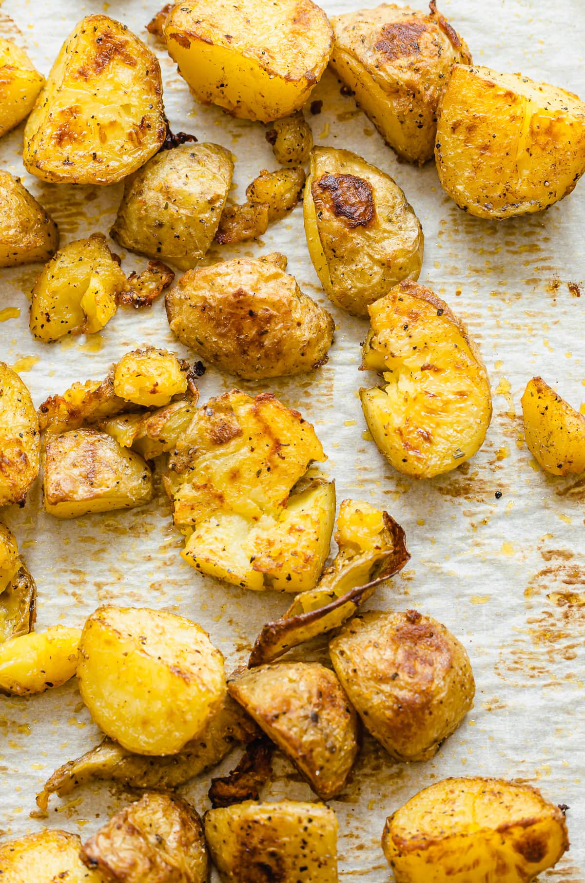 Smashed roasted potatoes on a parchment paper-lined baking sheet.