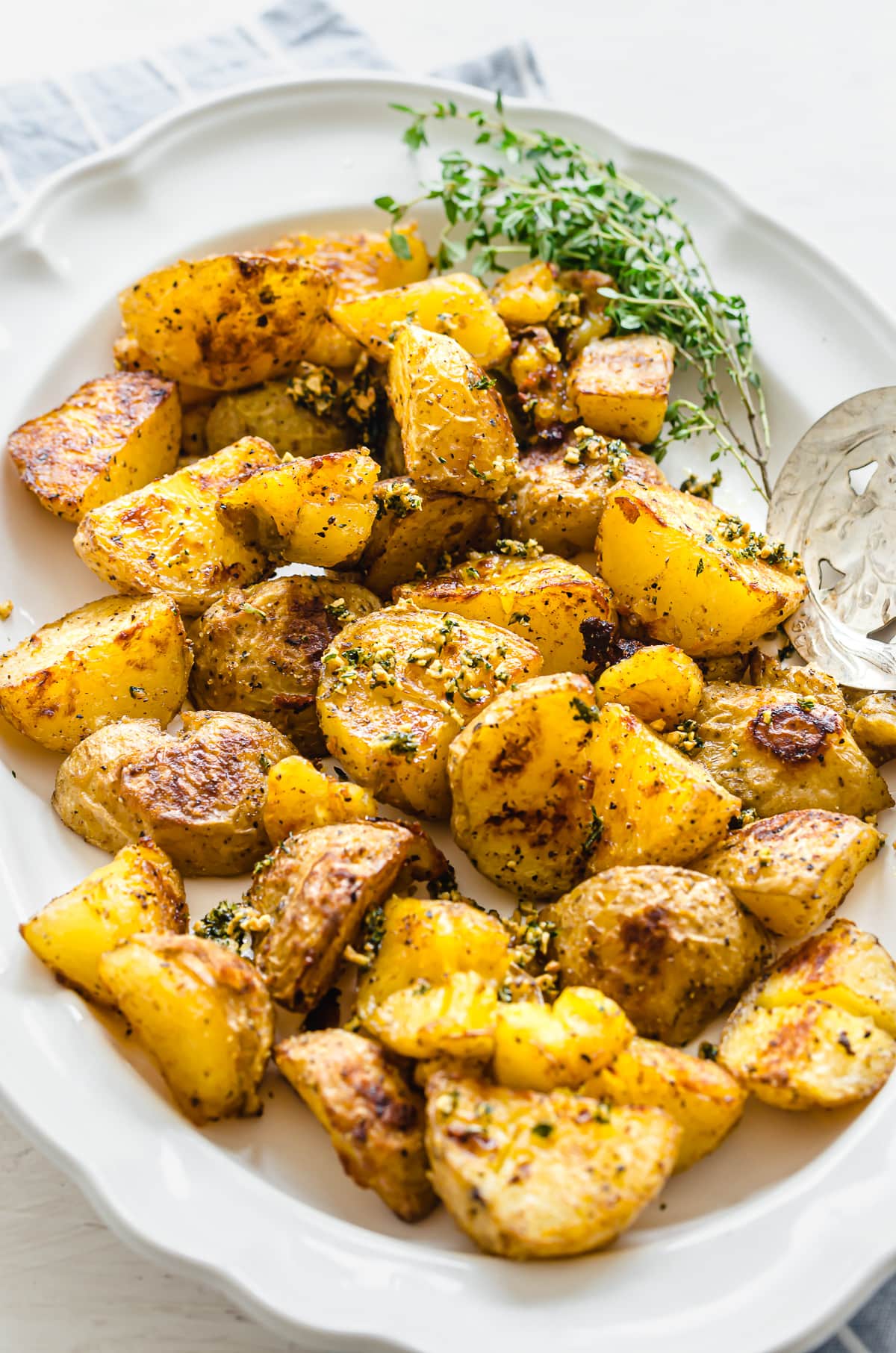 A close-up shot of roasted potatoes on a white serving platter.