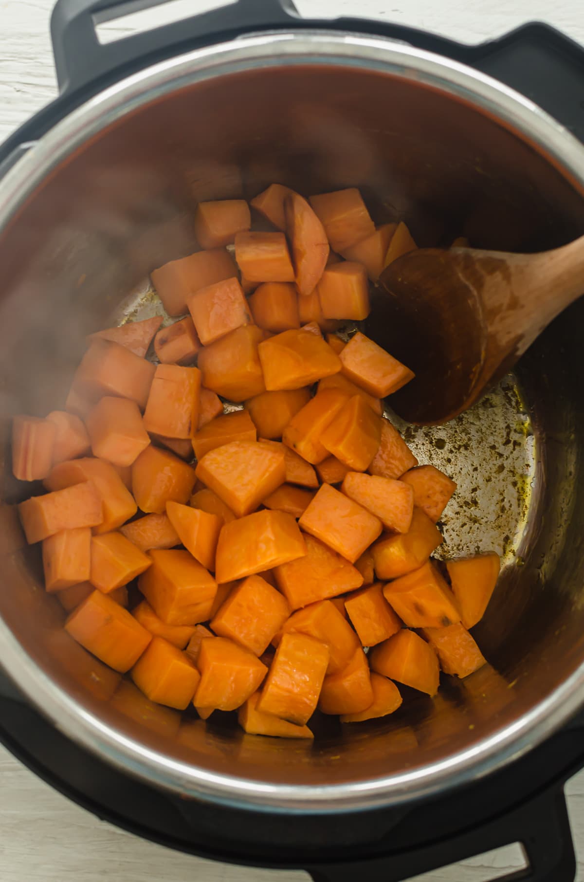 Sauteed cubed sweet potatoes in the bottom of an Instant Pot.