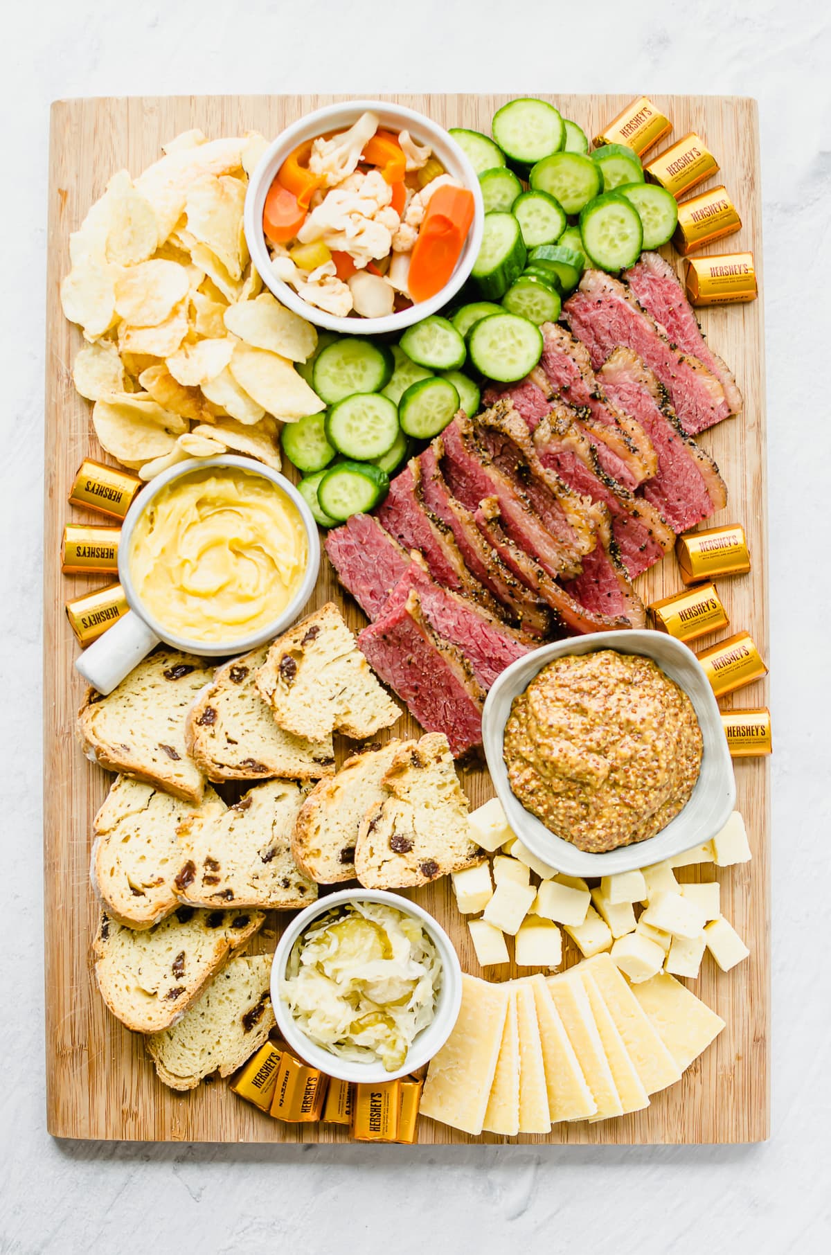 A St. Patrick's day themed snack board with corned beef, sauerkraut, soda bread, and other charcuterie items.